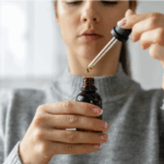 Woman using a CBD oil dropper from a dark glass bottle for wellness support