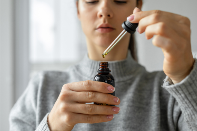 Woman using a CBD oil dropper from a dark glass bottle for wellness support