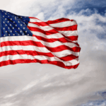 American flag waving against a blue sky, symbolizing patriotism and veteran-owned values.