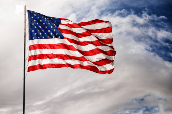 American flag waving against a blue sky, symbolizing patriotism and veteran-owned values.