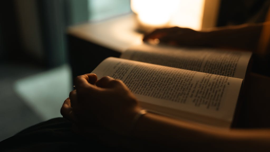 Person reading in bed with soft lighting after using CBD to sleep