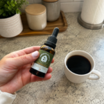 Adding CBD oil in coffee with an Innovative Extracts dropper bottle beside a morning latte.