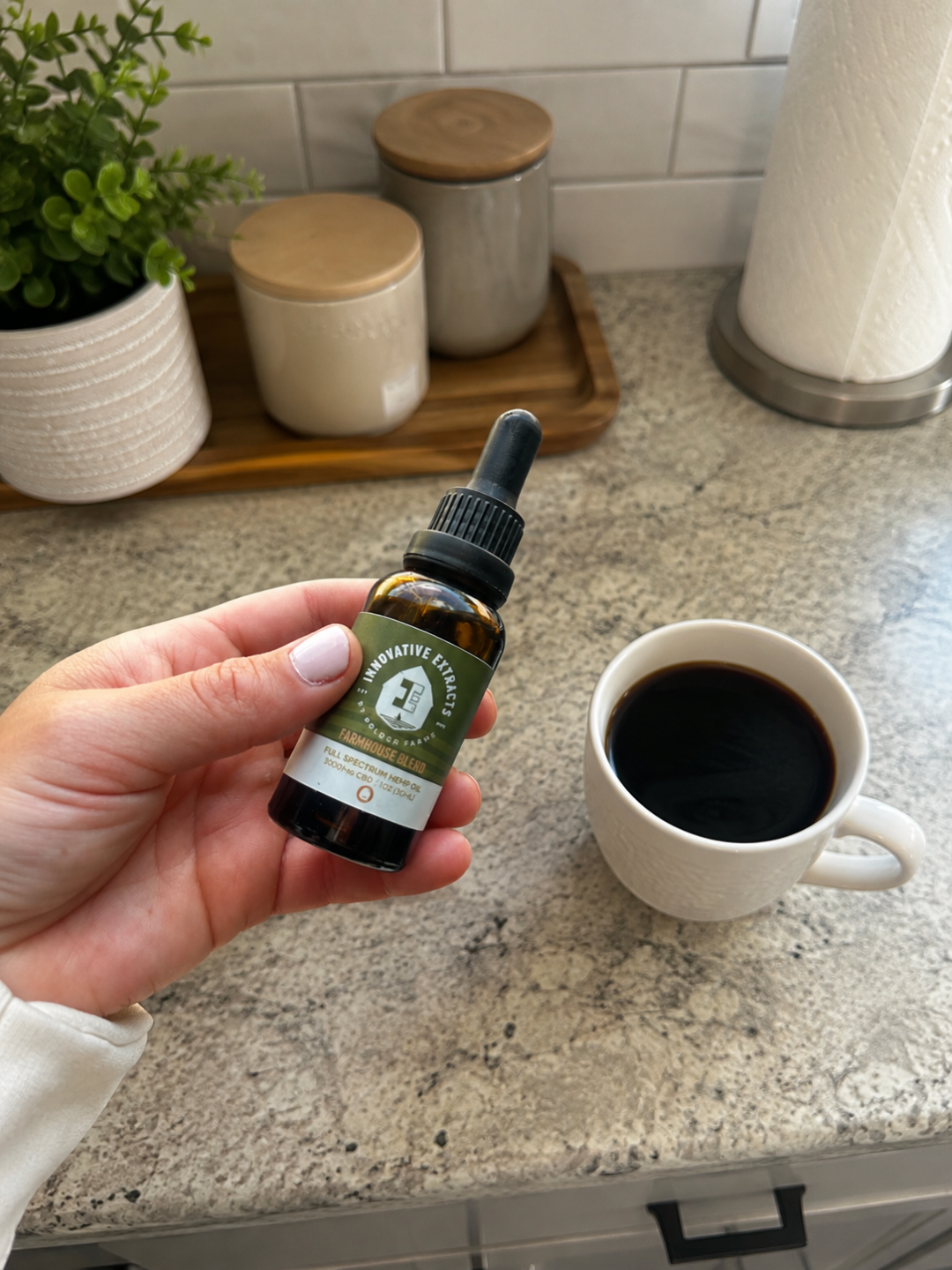 Adding CBD oil in coffee with an Innovative Extracts dropper bottle beside a morning latte.